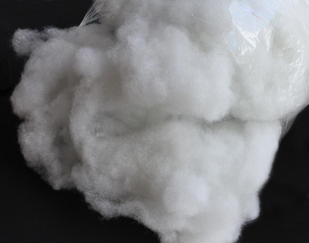 Polyester fiberfill stuffing material placed on a dark background.