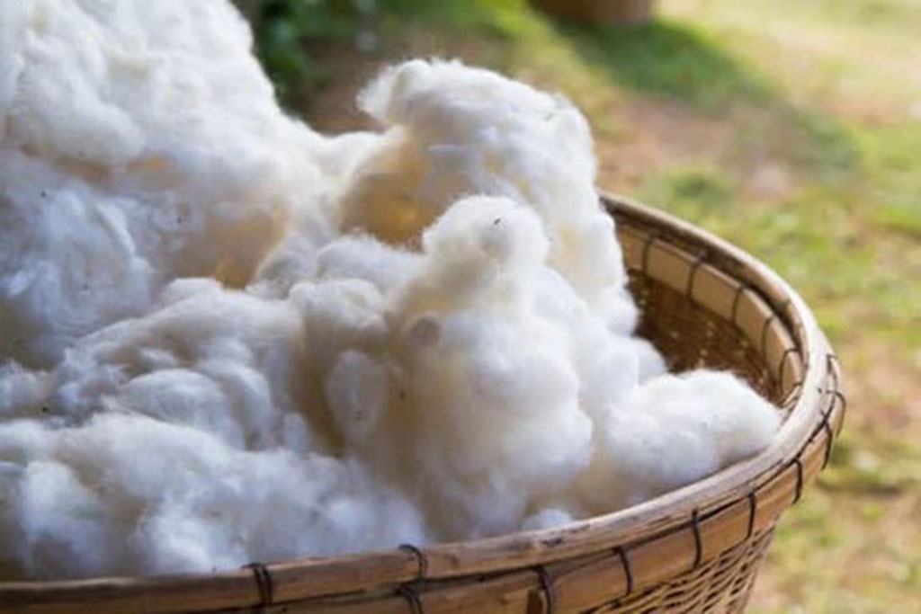 Basket filled with fluffy raw cotton fibers, commonly used as natural stuffing material for eco-friendly plush toys and handmade soft dolls.