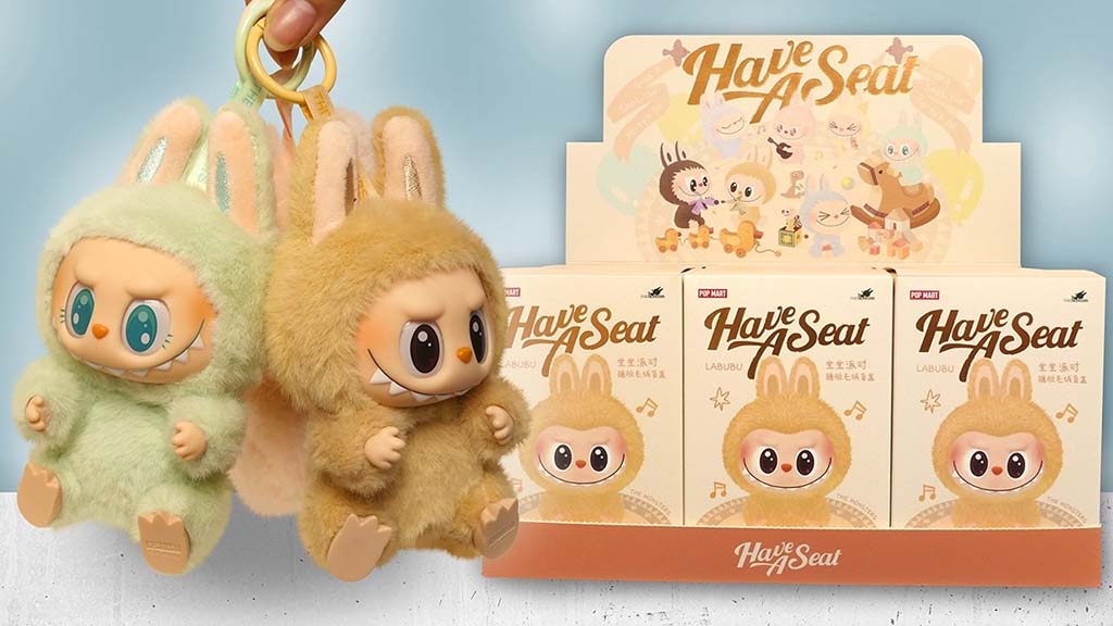 Two Labubu plush keychains in green and tan fur held by hand, shown beside Pop Mart “Have A Seat” blind box packaging display featuring illustrated characters.