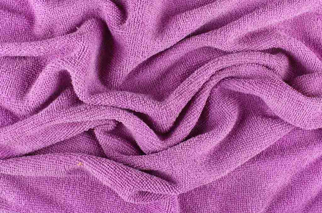 Close-up of soft purple microfiber fabric with textured surface and natural folds.