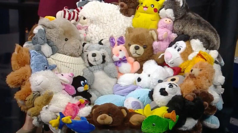 A large mixed pile of stuffed animals, including bears, bunnies, pandas, penguins, Pikachu, and other plush characters, arranged closely together in a colorful display.