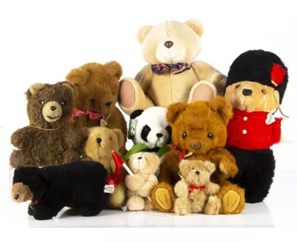 A group of classic teddy bears in various colors and styles, including a panda bear and a teddy dressed as a British guard.