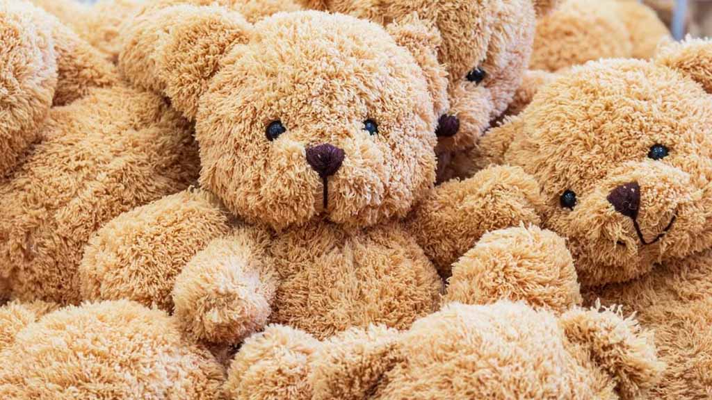 Pile of soft brown teddy bears with fluffy fur and cute stitched faces closely arranged together.