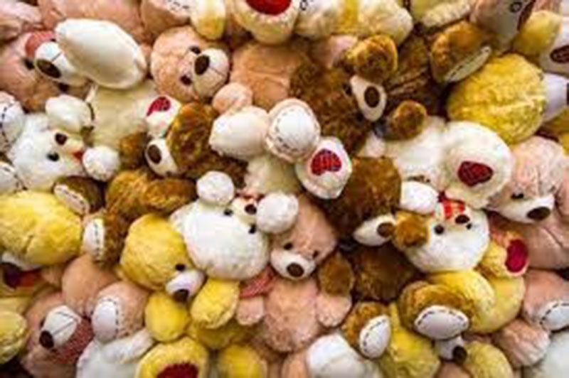 A large pile of assorted plush teddy bears in various colors including white, brown, yellow, and beige, stacked together in a dense heap.
