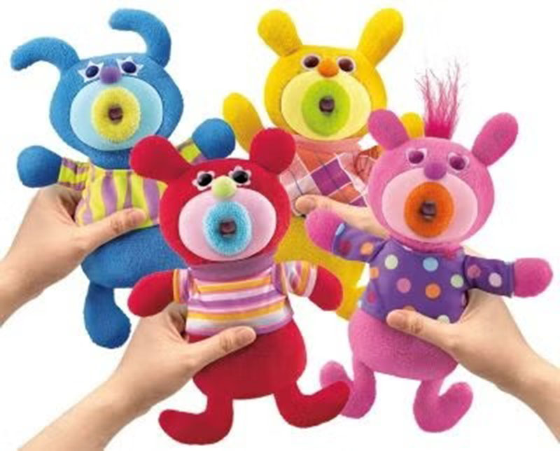 Four colorful plush monster toys held in hands, featuring bright blue, red, yellow, and pink bodies with round textured mouths and playful expressions.
