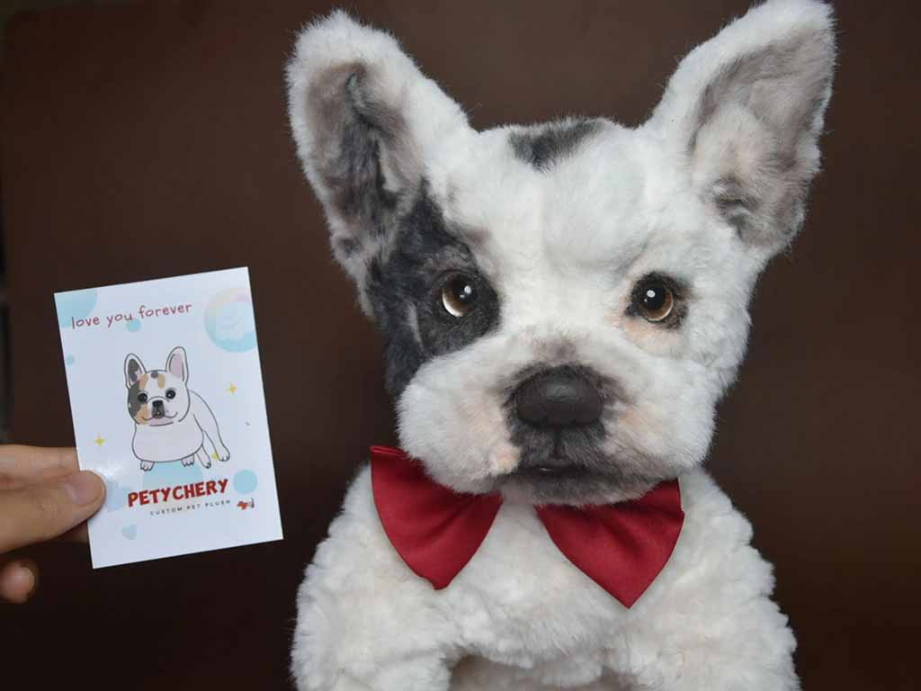 Handmade custom dog plush resembling a black-and-white French bulldog, wearing a red bow tie and displayed beside a small illustrated pet card.