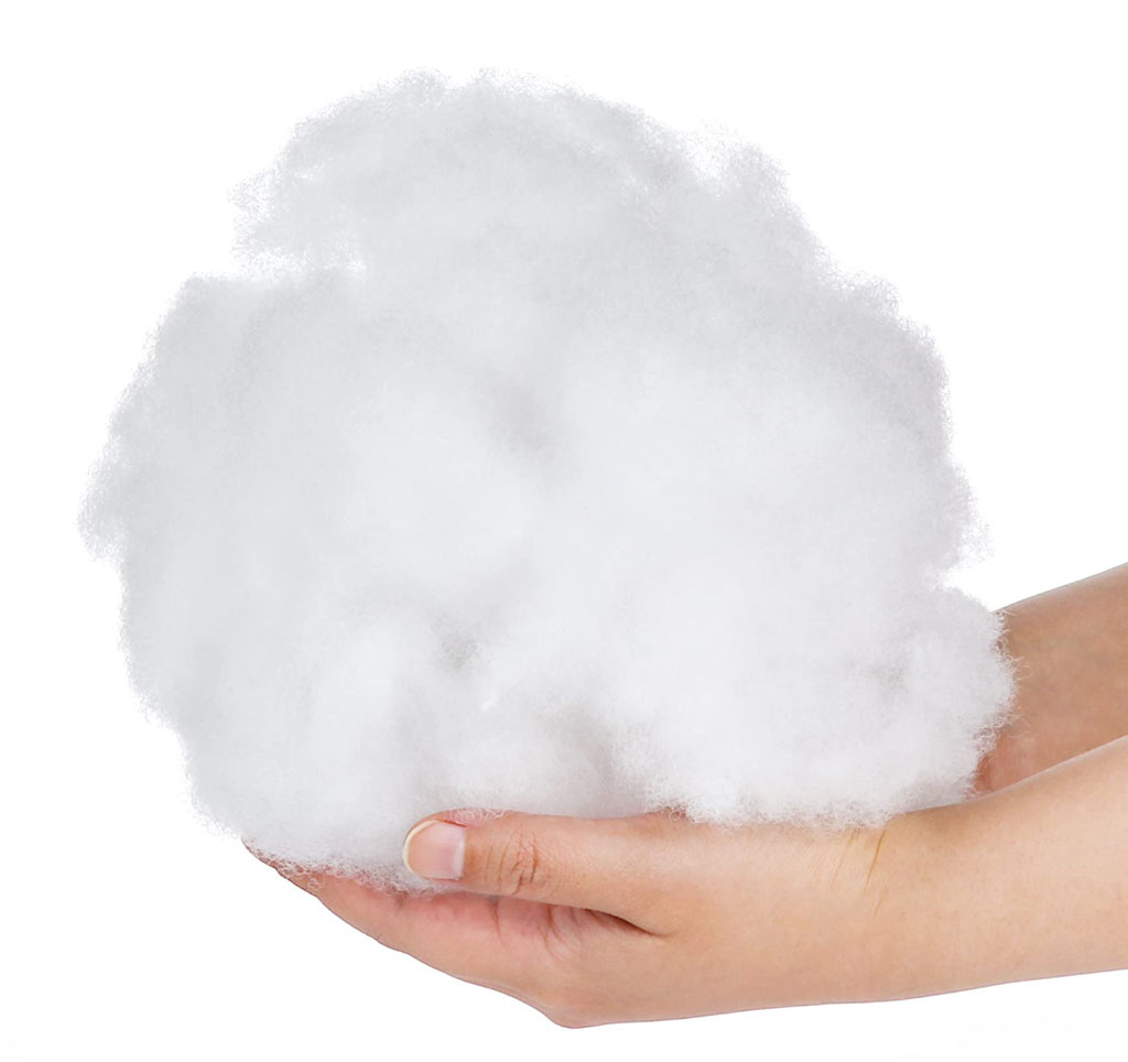 Hand holding a fluffy white polyester fiberfill stuffing used for plush toys, pillows, and soft toy filling