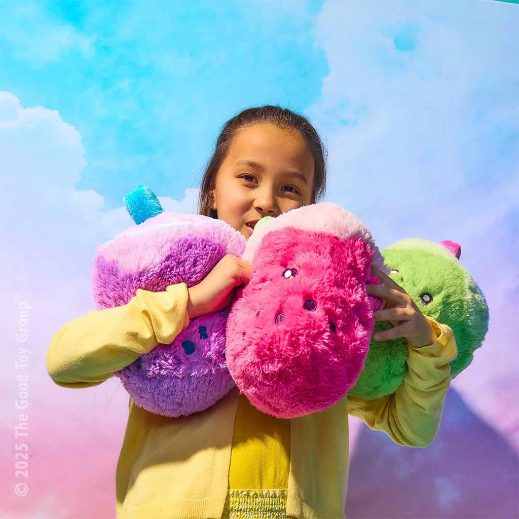 Child holding three colorful plush pillow toys—purple, pink, and green—against a bright pastel sky background, showcasing soft textures and playful design.