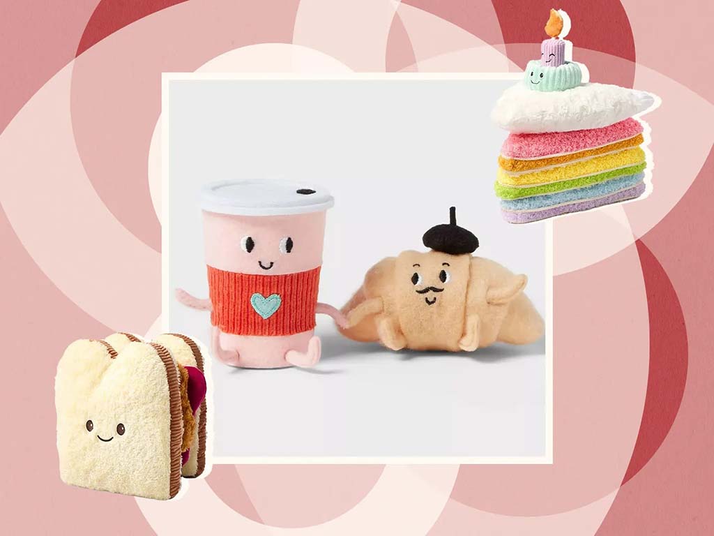 Cute food-themed plush toys including a smiling takeaway coffee cup and a croissant character, displayed on a pink illustrated background with playful dessert-inspired accents.