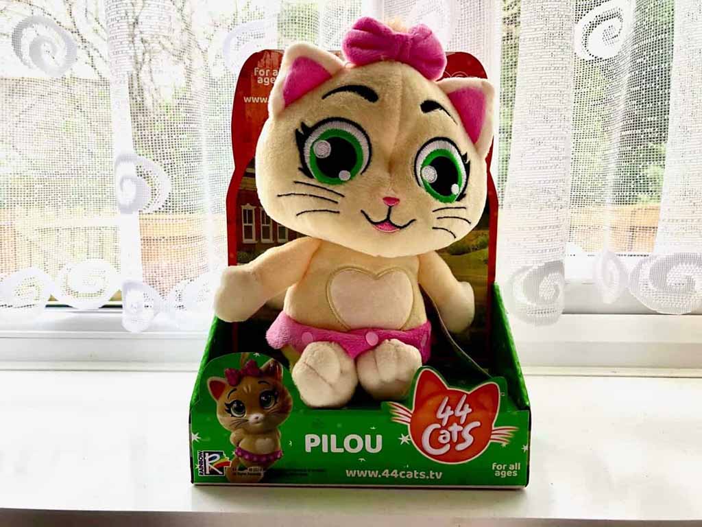 Musical plush cat toy with green eyes and pink bow, wearing pink shorts, displayed in branded 44 Cats ‘Pilou’ retail packaging.