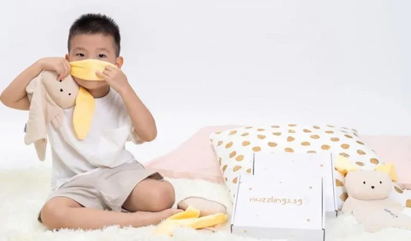 Young child sitting on a soft surface while interacting with a hypoallergenic stuffed animal, demonstrating gentle play, soft fabric texture, and child-safe plush design in a supervised environment.