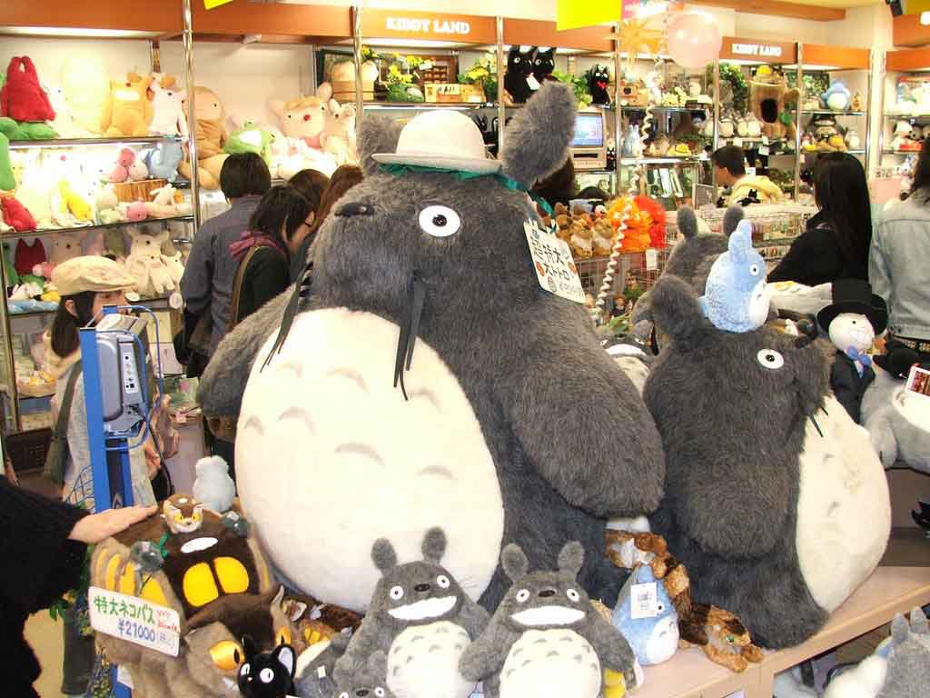 A retail display featuring oversized Totoro plush toys surrounded by smaller character plushies, highlighting the popularity of large stuffed animals, licensed character designs, and in-store plush merchandising for gift shops and specialty toy retailers.