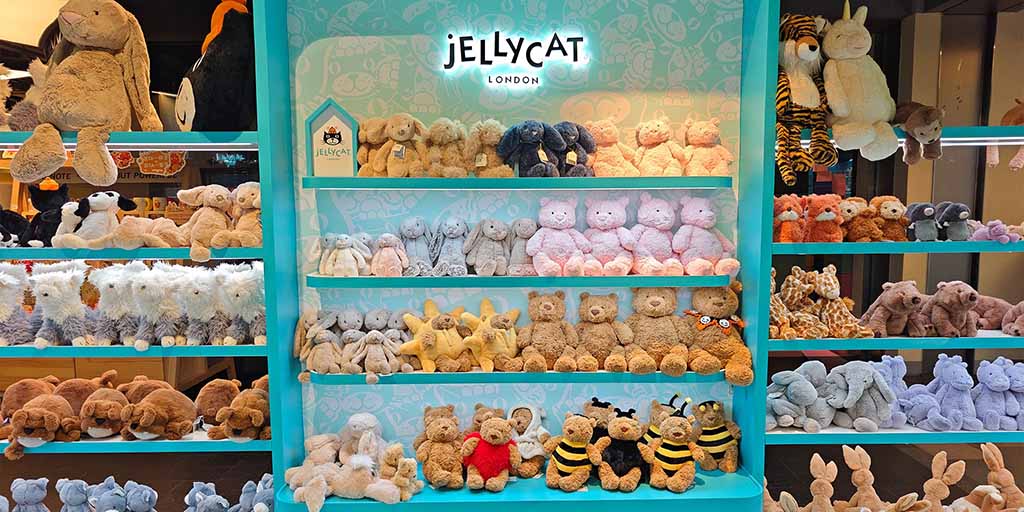 Jellycat London plush toys neatly displayed on retail shelves, showcasing soft stuffed animals in coordinated colors and styles, ideal for toy stores, gift shops, premium plush retail displays, and branded in-store merchandising inspiration.