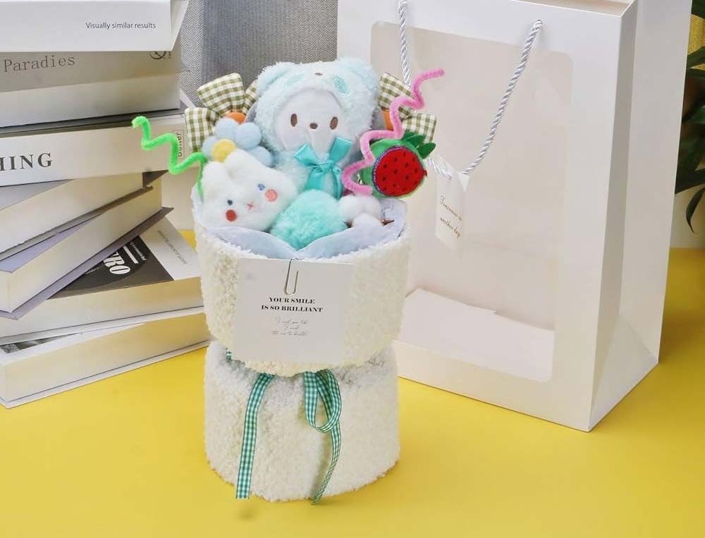Soft plush bouquet featuring pastel teddy bears, small plush toys, and colorful decorative elements arranged in a fluffy white holder with a ribbon.