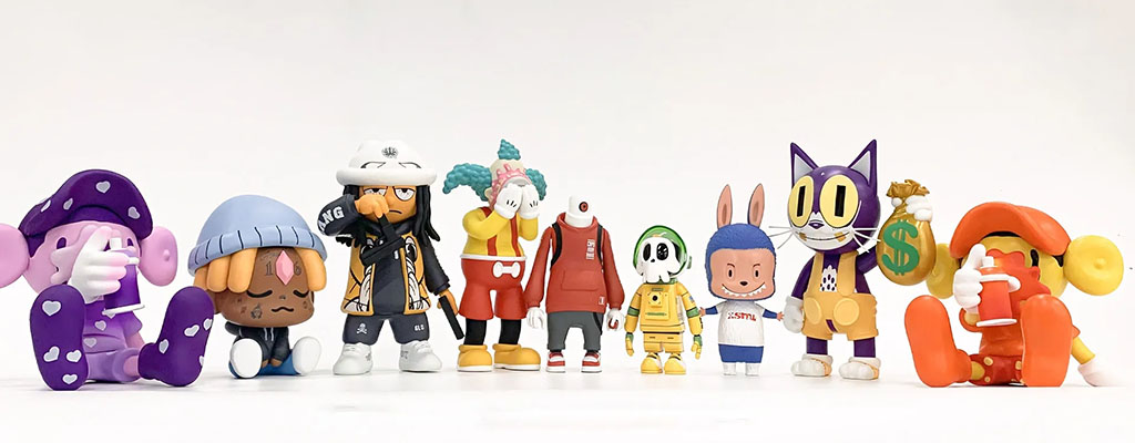A lineup of colorful designer vinyl art toys featuring unique characters in various outfits and poses, arranged side by side on a clean white background.