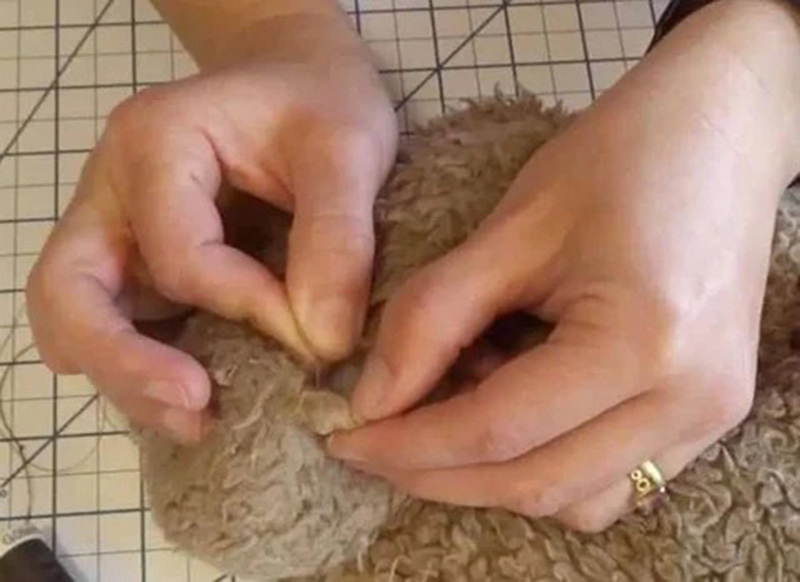 Close-up of hands hand-stitching a plush toy seam, demonstrating professional plush toy repair and finishing techniques used in handmade and factory plush production.