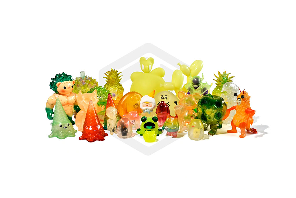 A vibrant assortment of small designer resin art toys in various translucent colors and shapes, including animals, trees, and abstract characters, arranged together on a white background.