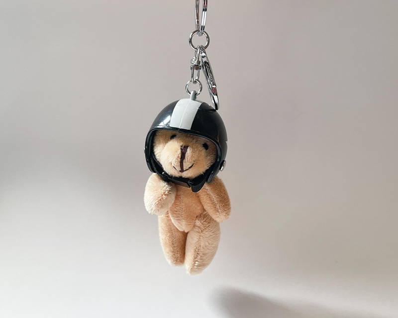 Mini teddy bear keychain wearing a black helmet.