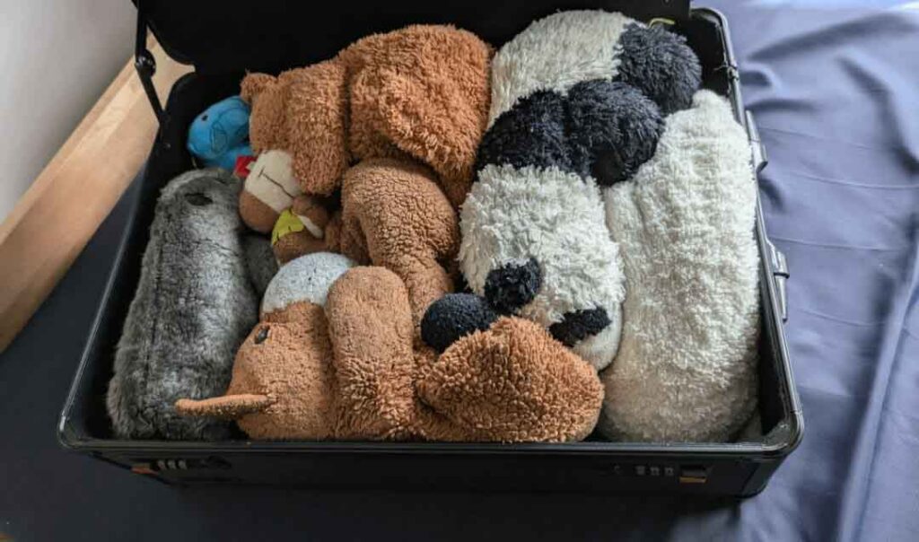A storage bin filled with assorted plush toys and stuffed animals, neatly arranged to maximize space and protect their shape, illustrating practical organization and storage solutions for plush collections in bedrooms, dorm rooms, or home environments.