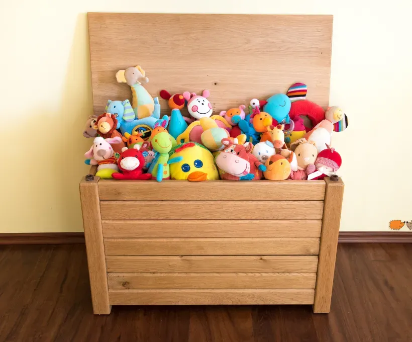 Wooden toy chest filled with colorful plush stuffed animals.