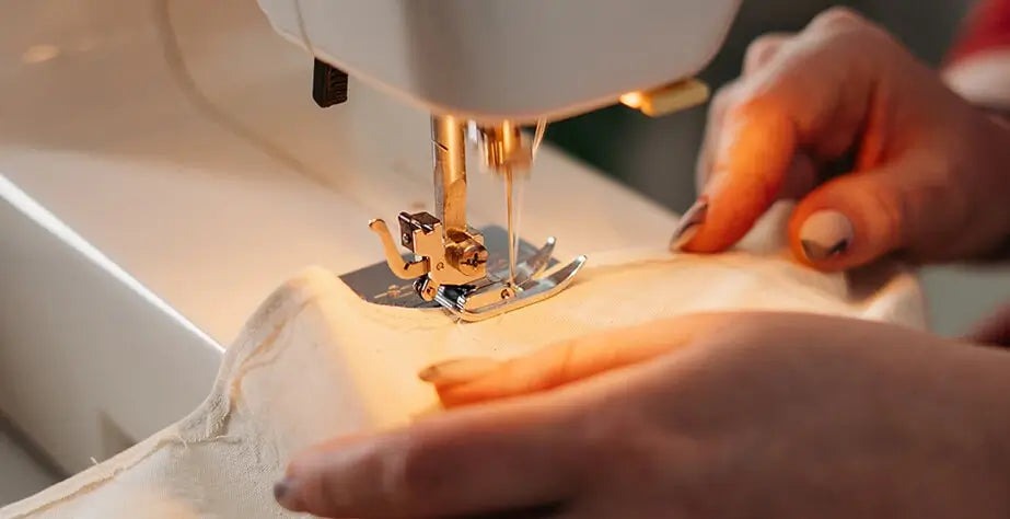 Close-up of hands guiding fabric through a sewing machine to stitch a seam for a plush toy.