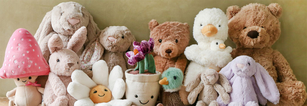A curated group of soft plush toys including teddy bears, bunnies, duck plushies, and decorative character dolls arranged together, showcasing premium plush textures, neutral pastel colors, and gift-ready stuffed animal designs suitable for boutique toy stores and baby gift markets.