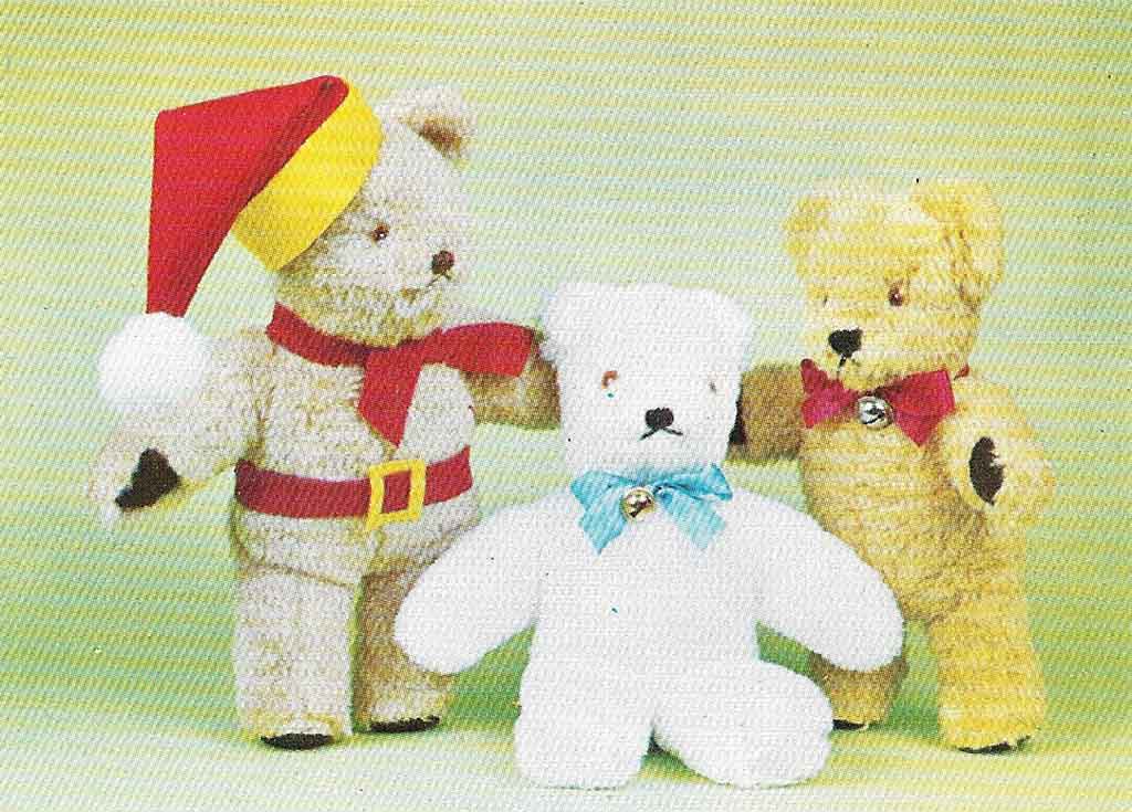 Three vintage-style teddy bears standing together against a light green background: one dressed in a Santa hat and belt, one white bear with a blue bow, and one golden bear with a red bow.