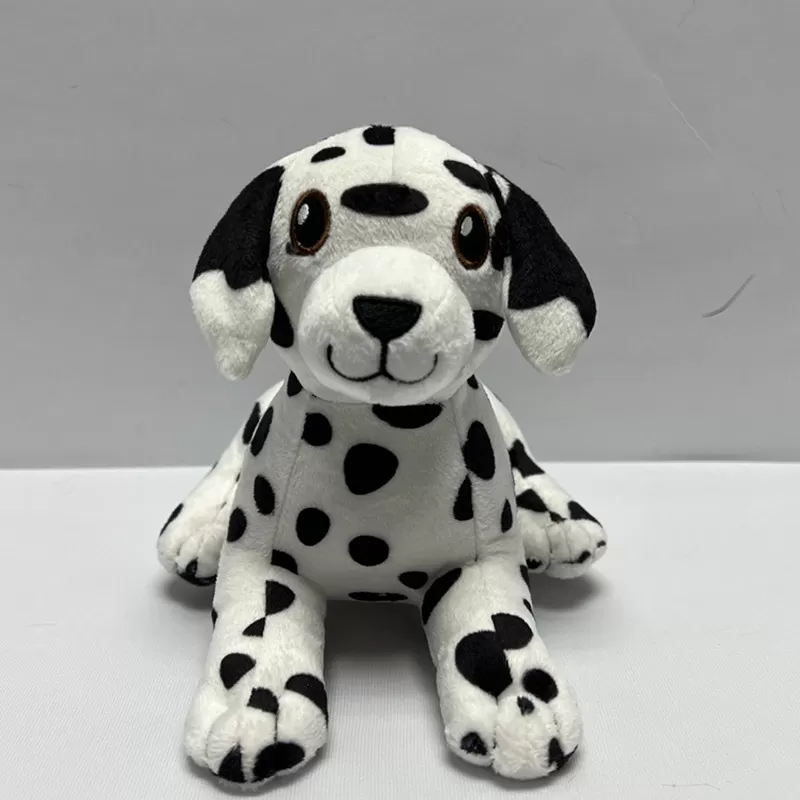 A cute black-and-white Dalmatian puppy plush toy with floppy ears, embroidered smile, and scattered black spots, sitting against a plain light background.