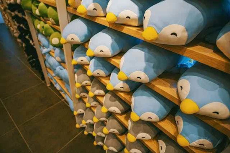 Rows of colorful penguin plush toys stacked on shelves.