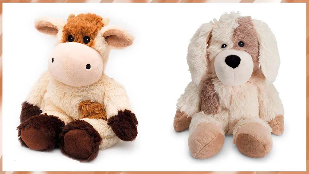 Two soft stuffed animals, one cow plush and one floppy-eared dog plush, sitting side by side against a white background.