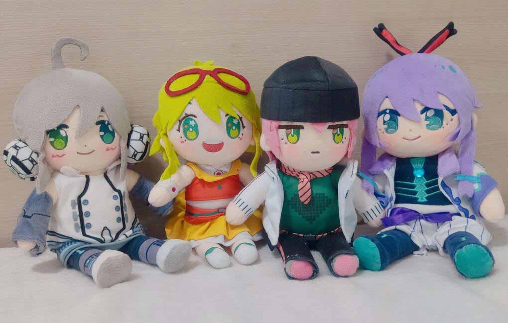 Four anime-style plush dolls with colorful hair and detailed costumes sitting together.