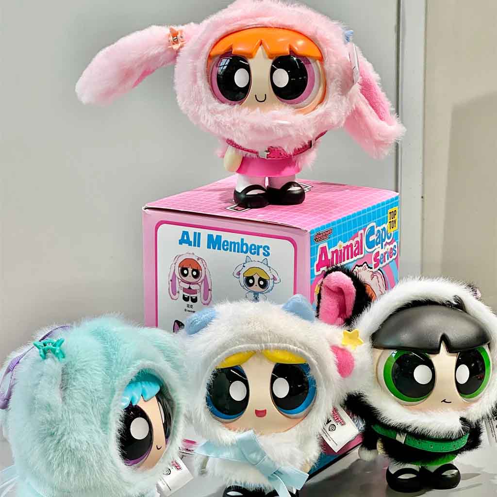 Cute Powerpuff Girls collectible figures dressed in fluffy animal cape outfits, displayed with their pink series box behind them. Blossom, Bubbles, and Buttercup each wear different plush animal hoods, showcasing the Animal Cape blind box series.
