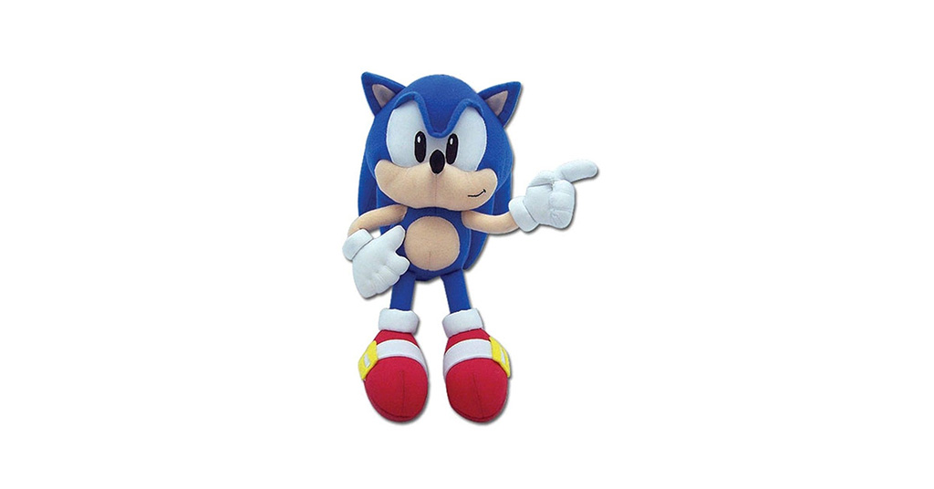 Stuffed plush toy of classic Sonic the Hedgehog standing upright on a white background, with blue body, beige muzzle and belly, white gloves, and red shoes, pointing forward with one hand.