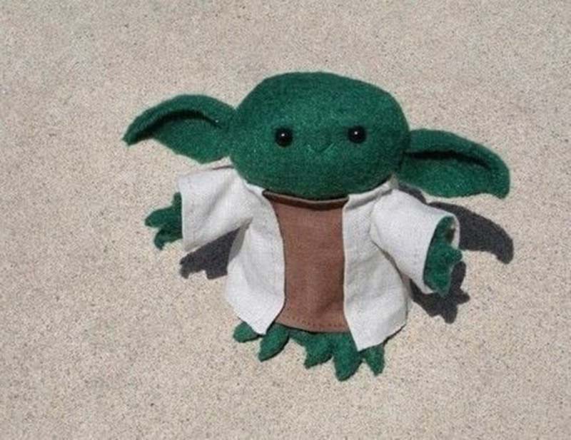 Handmade green alien plush doll with wide ears, dressed in a white robe and brown tunic, displayed on a light outdoor surface for a cute craft showcase.