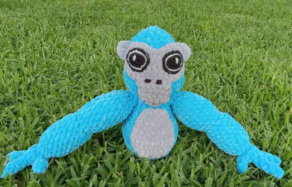 Blue and gray textured gorilla plush with long outstretched arms sitting on green grass, handmade with soft bubble-minky fabric.