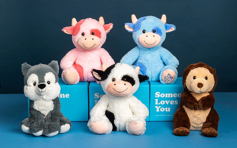 Assorted plush animal toys displayed on blue boxes with smiling faces