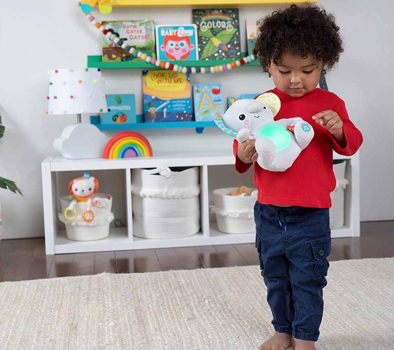 Toddler playing with light-up interactive plush toy in a colorful playroom