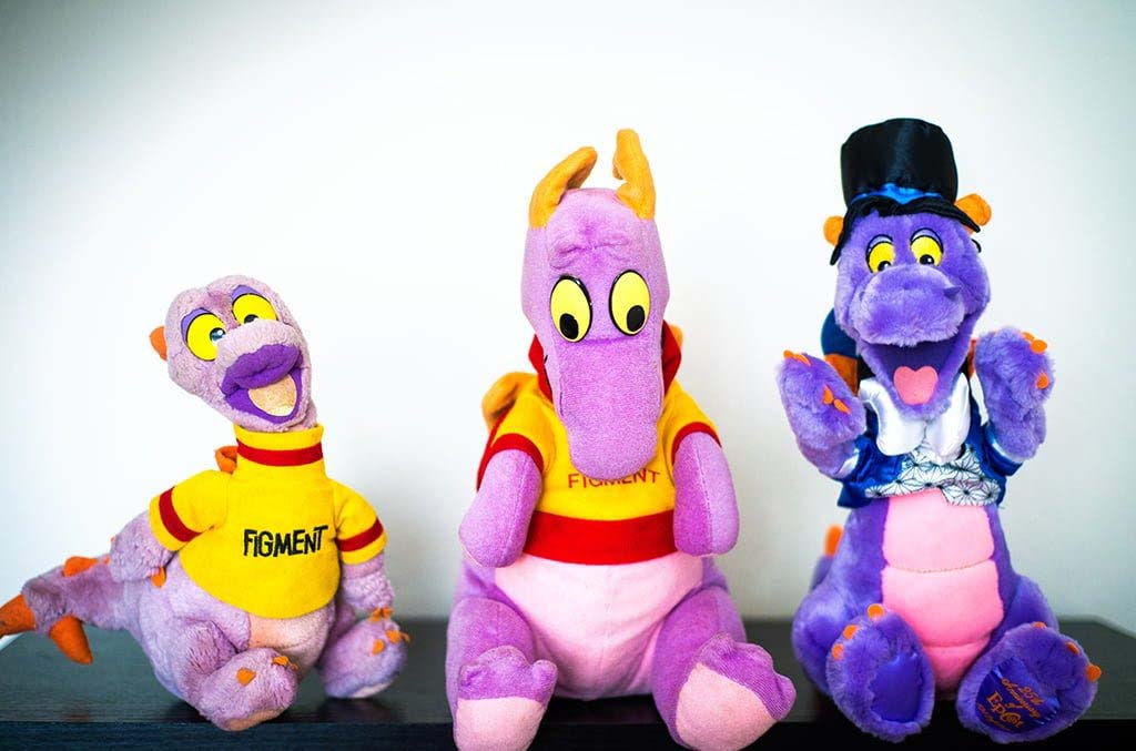Three purple Figment dragon plush toys displayed side by side