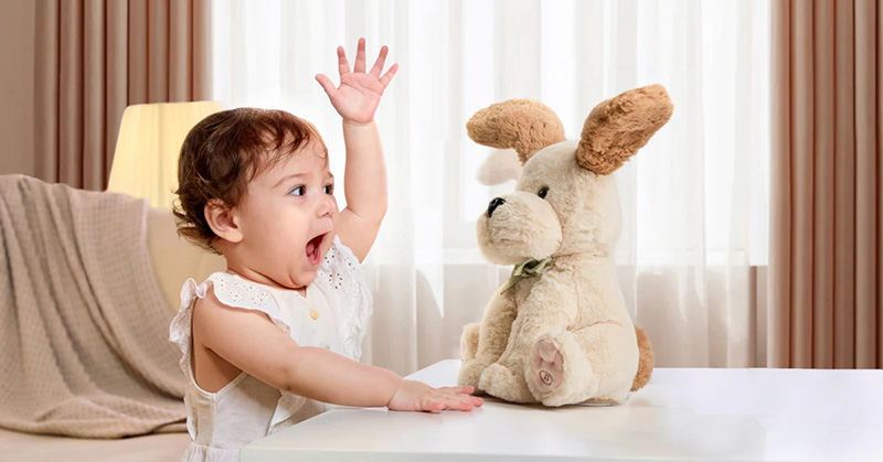 Baby reaching excitedly toward a plush dog toy on a table