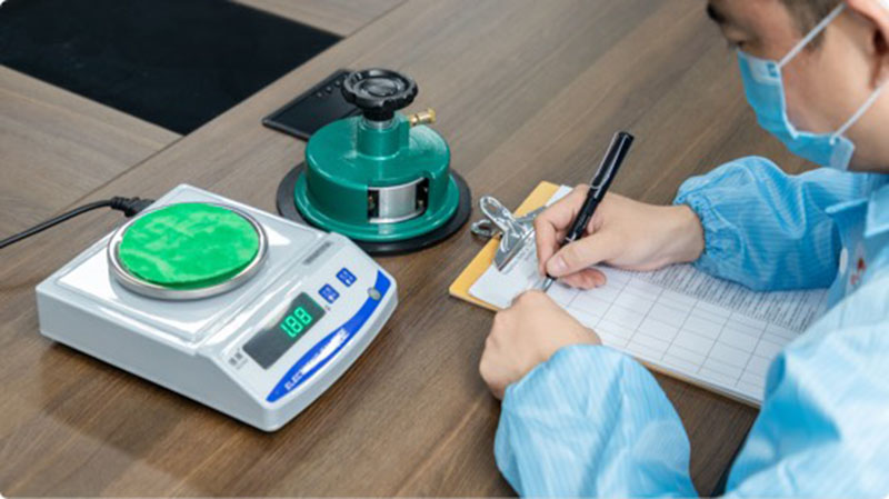 Staff measure material weight and record data to ensure accuracy and quality compliance.