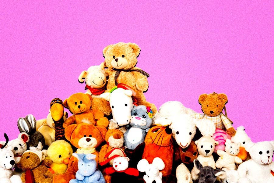 A colorful pile of teddy bears and plush animals stacked together against a bright pink background
