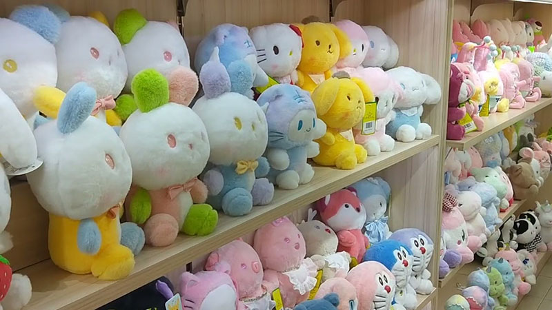 Rows of cute plush character toys neatly displayed on wooden shelves in a toy shop showroom.
