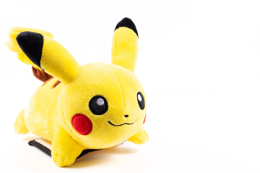 A bright yellow character plush toy lying down on a white background, with long ears, red cheeks, and embroidered eyes and smile.