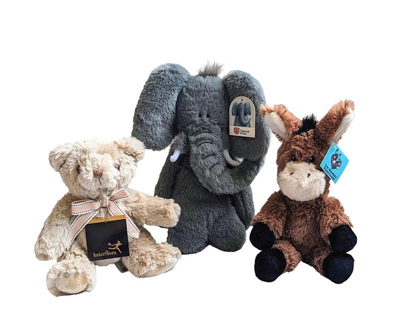 Three plush animals on a white background: a teddy bear, a gray elephant, and a brown donkey with hang tags.