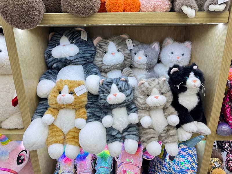 A selection of plush toys displayed on shelves, showcasing different styles, colors, and character variations.