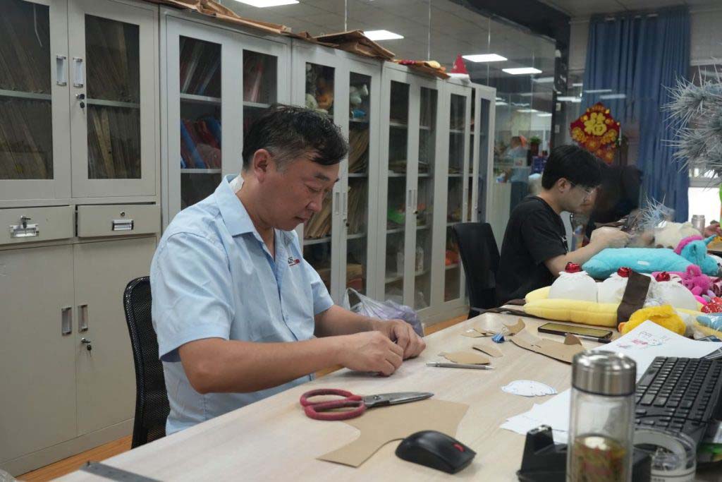 Technicians work on patterns and sample details to prepare plush toys for prototype and production stages.