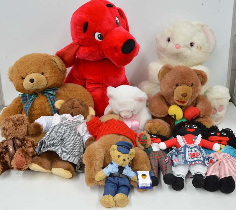 Assorted stuffed animals displayed together, including teddy bears, a large red plush dog, and dressed plush dolls on a white background