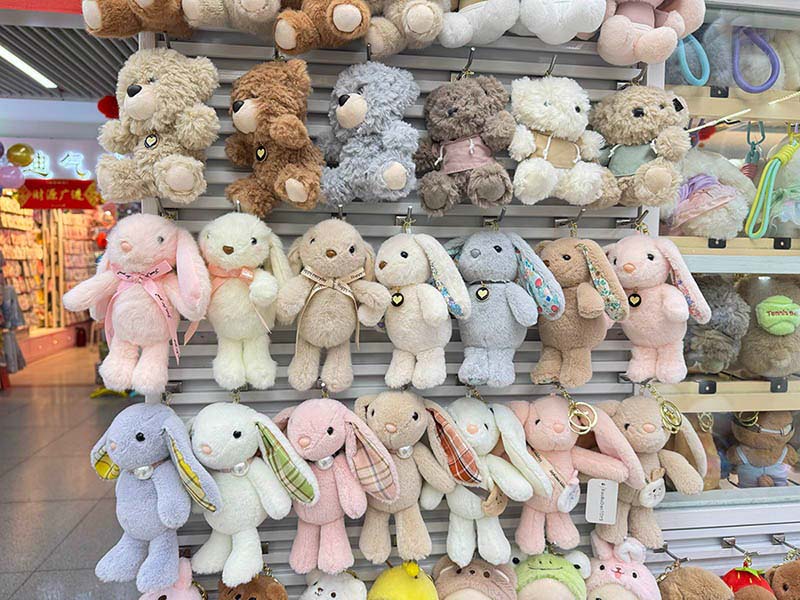 Soft bunny plush toys in pastel colors displayed on a retail wall rack, highlighting variety and gift-ready appeal.