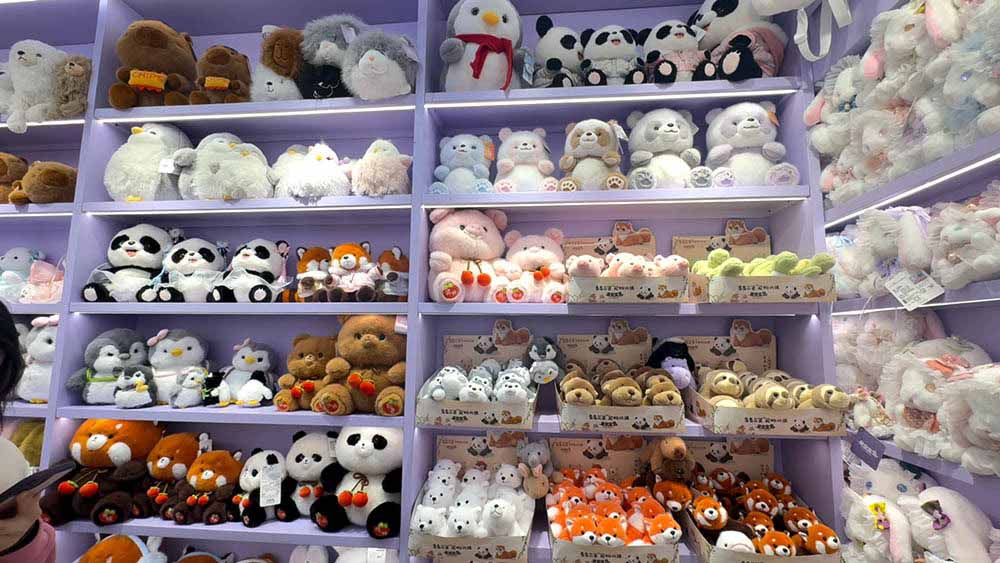 Wide assortment of plush animals arranged on pastel-colored shelves, showcasing variety and organized retail presentation.