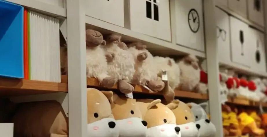 Assorted plush toys neatly arranged on store shelves, emphasizing organized retail presentation and soft character designs.